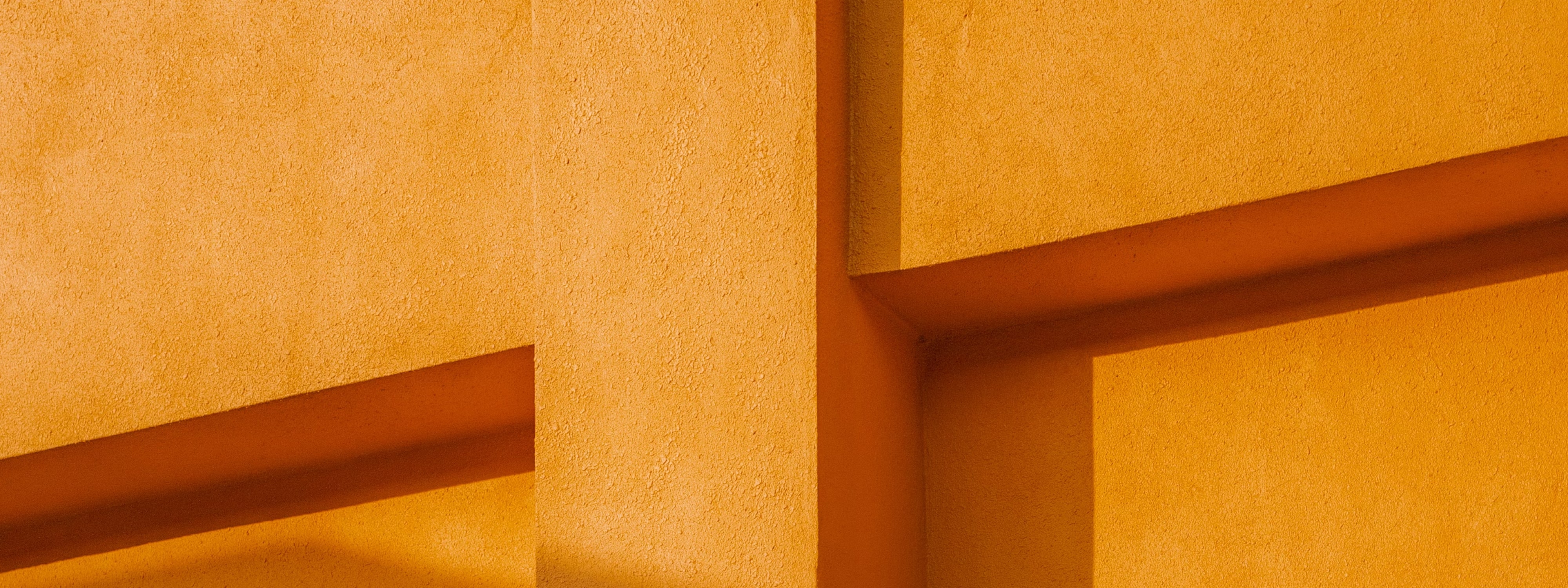 Abstract yellow wall with geometric shadows and textured surface