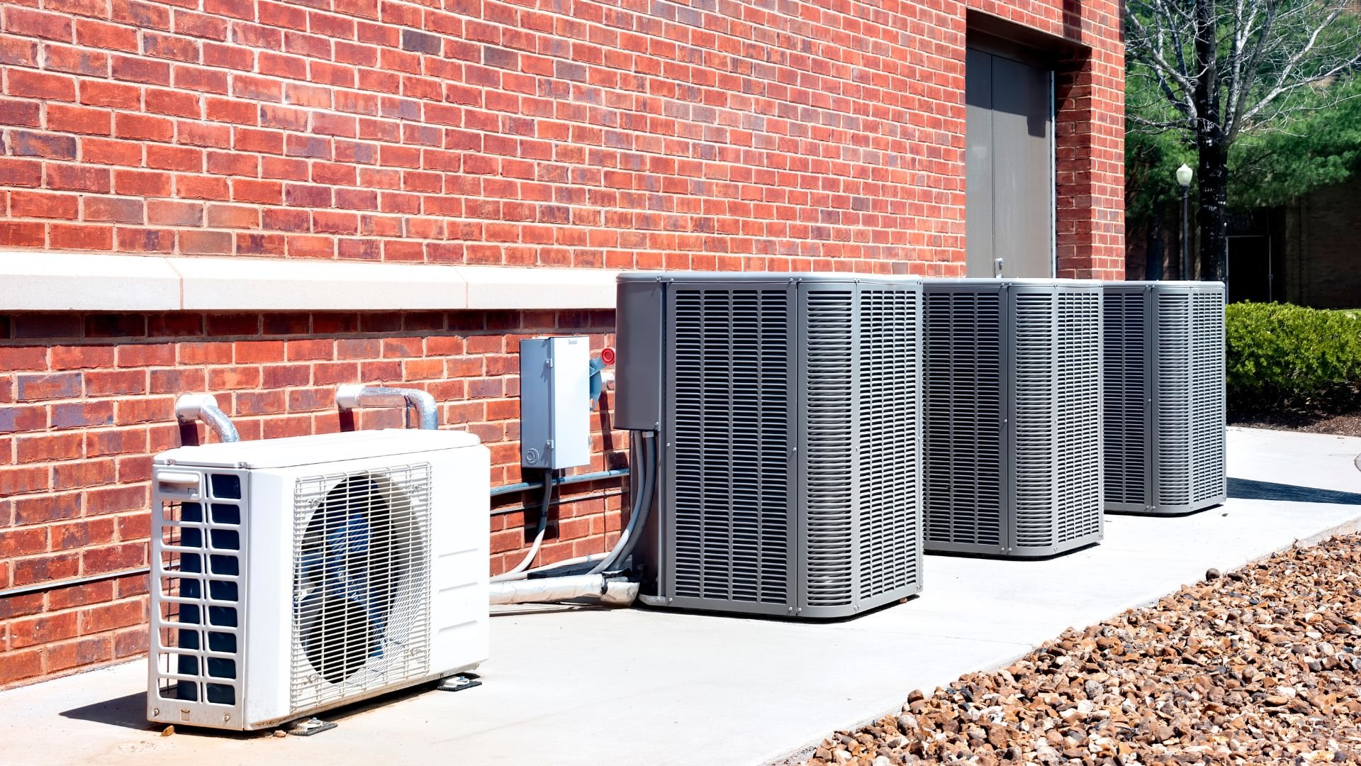 Multiple air conditioning units next to red brick building exterior