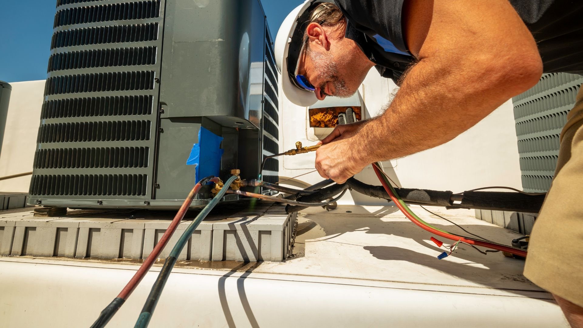 HVAC technician repairing air conditioning unit on rooftop
