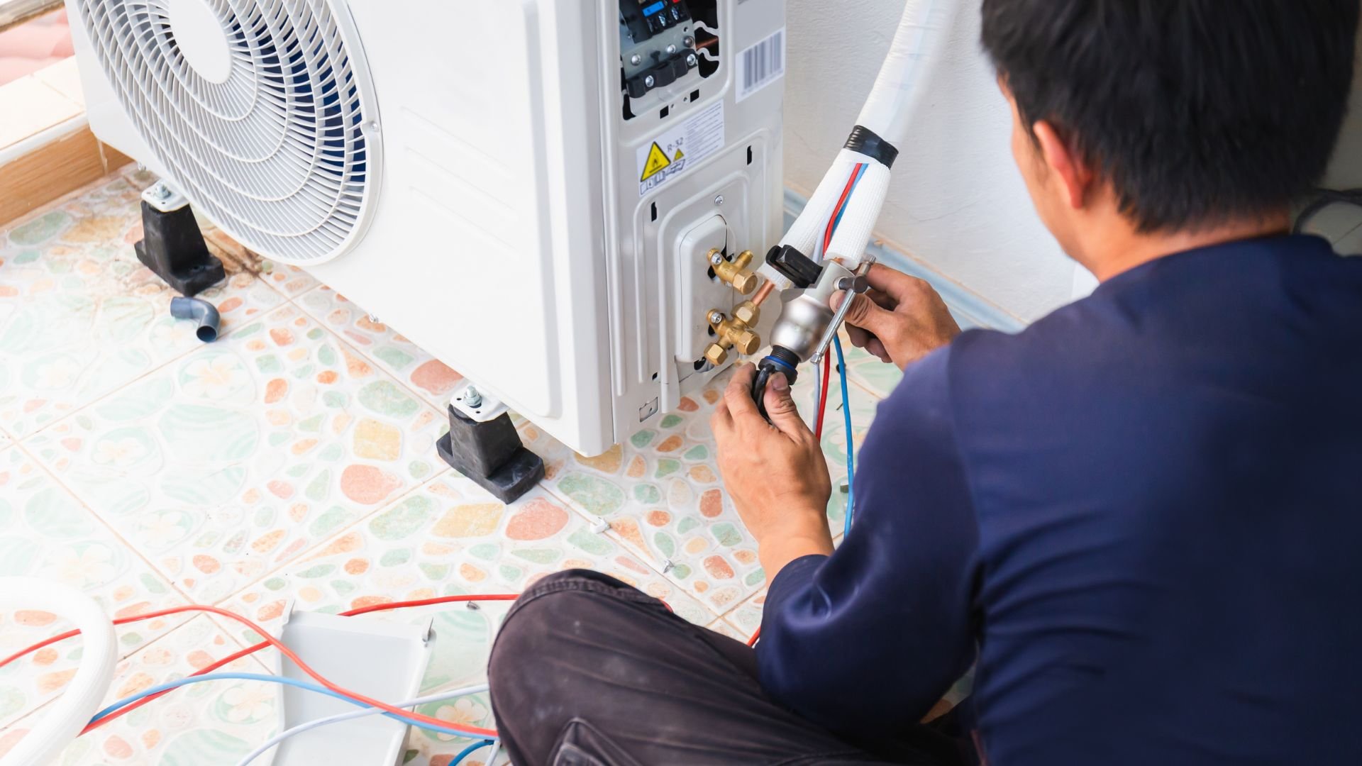 Technician installing or repairing an air conditioning unit with tools