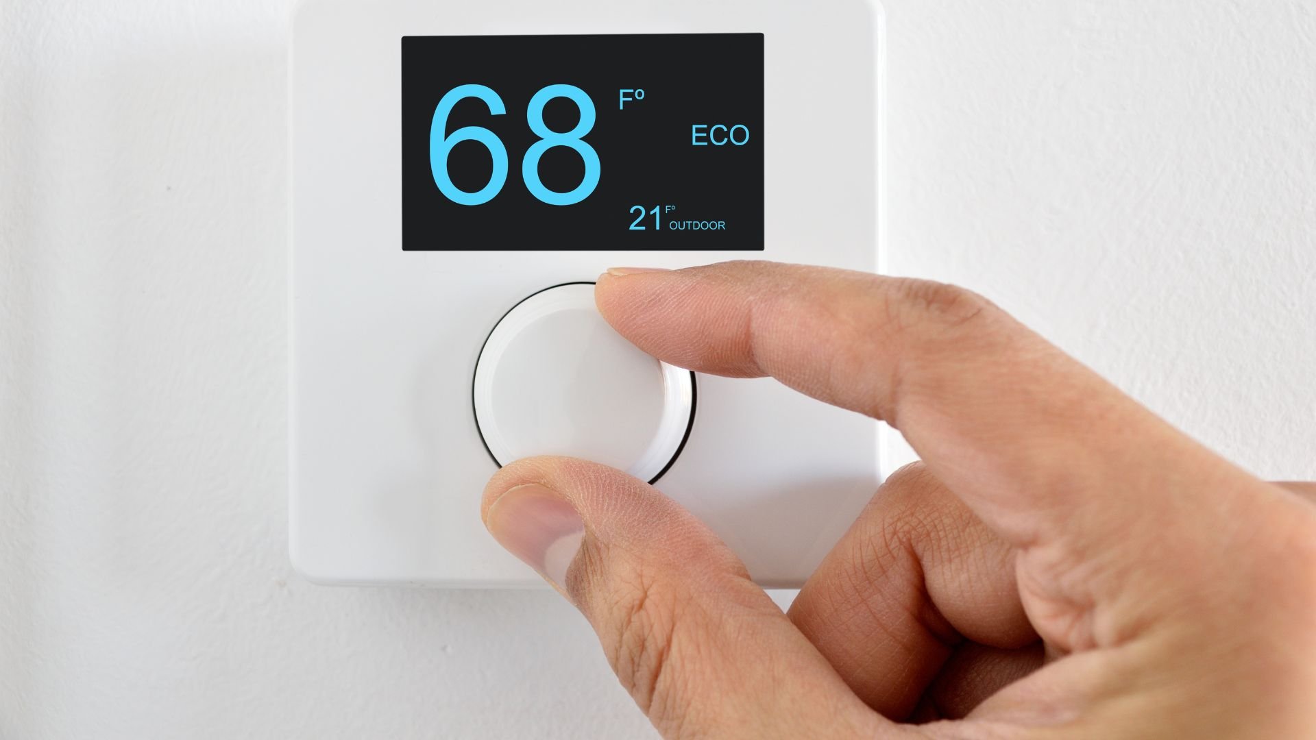 Hand adjusting digital thermostat set to 68 degrees Fahrenheit