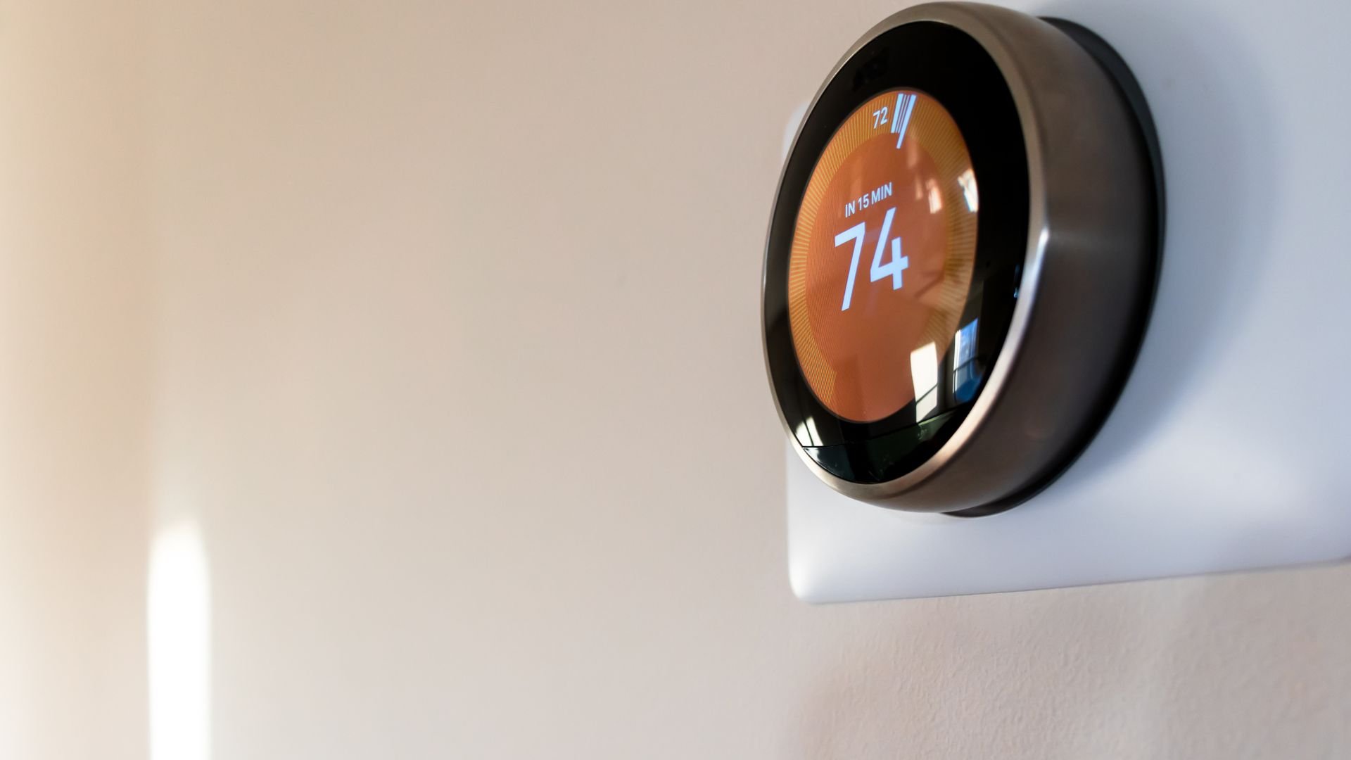 Modern digital thermostat showing temperature of 74 degrees on wall